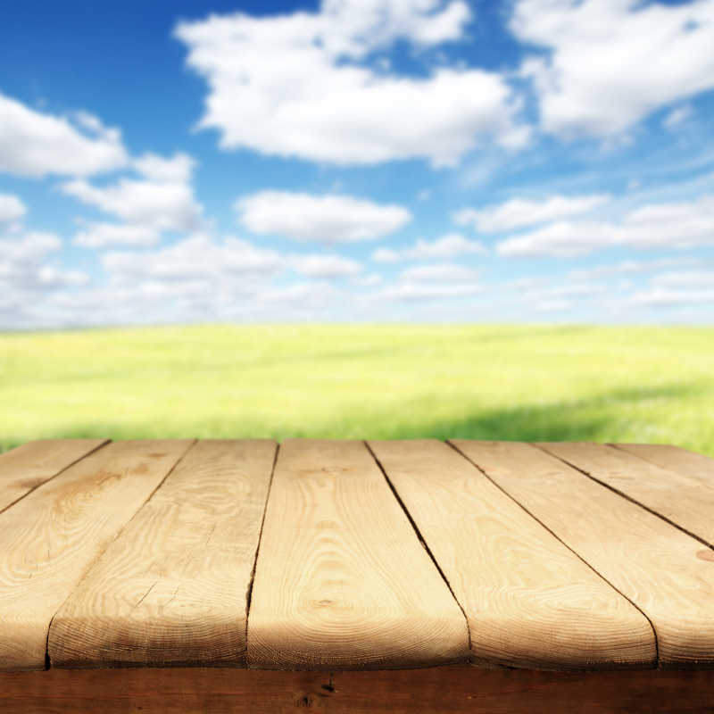 蓝天下的绿色草坪背景前的木桌