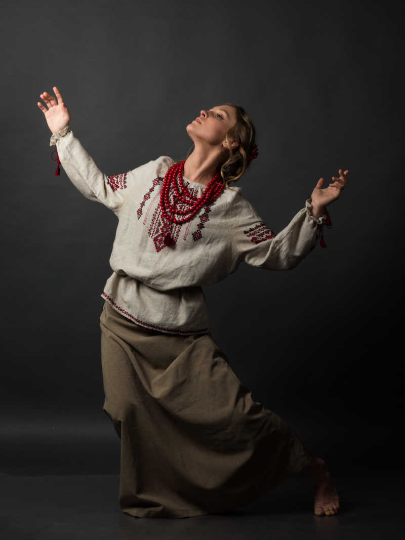 灰色背景下穿刺绣衣服跳舞的乌克兰美女