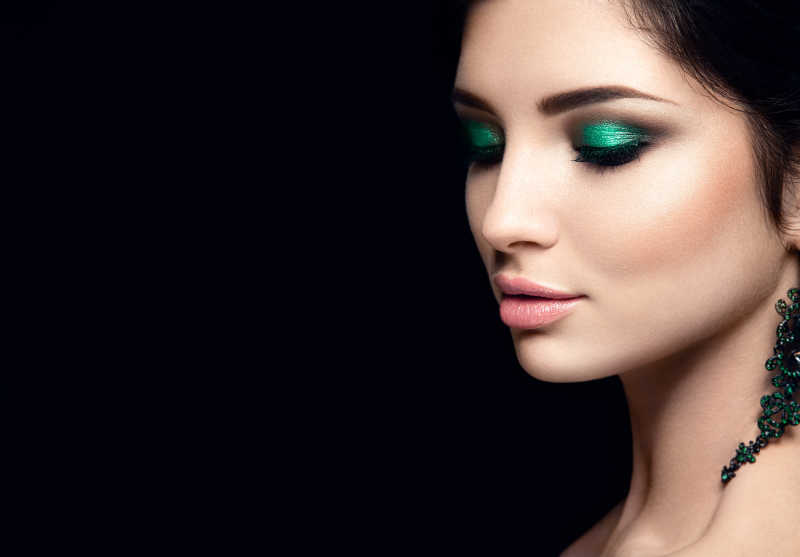 黑色背景下的画着绿色眼妆的美女