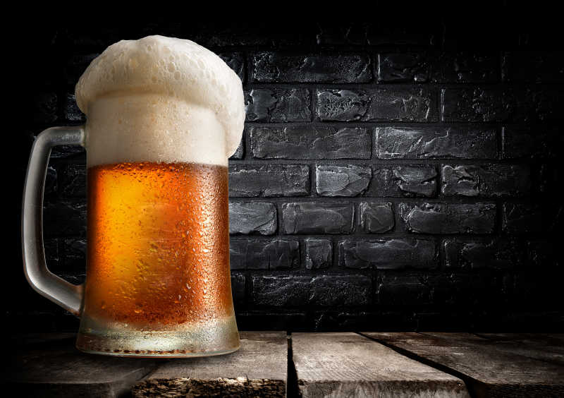 黑砖墙的桌子上的一杯啤酒