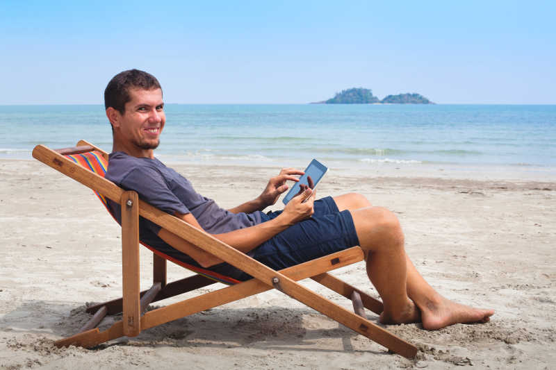 正在海滩休闲椅上微笑的男子