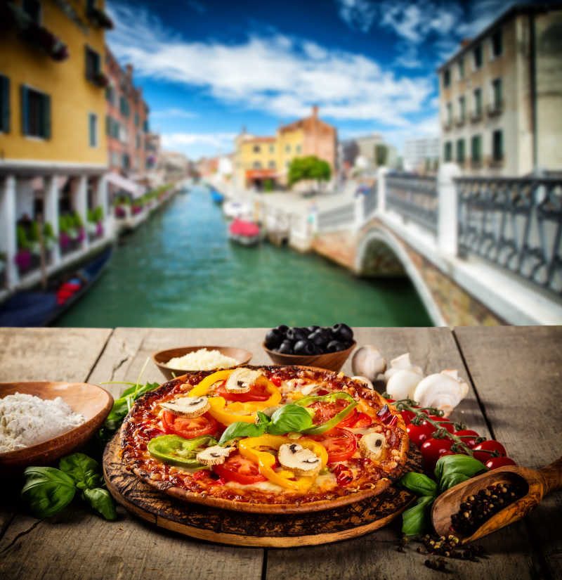 河流两旁的城市虚化背景下的木桌上的披萨