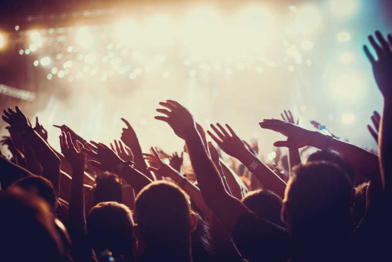 在音乐节上举起手来的观众和舞台上方的灯光