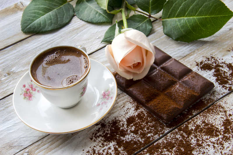 土耳其咖啡桃色玫瑰和木桌上的巧克力片