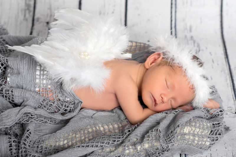 灰色毛毯下作天使打扮的婴儿