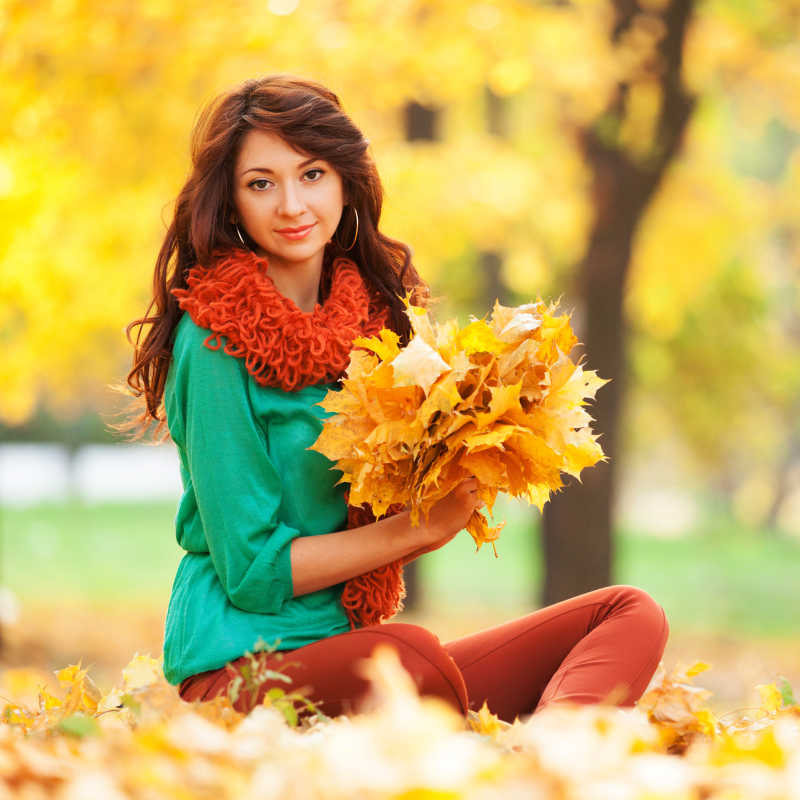 秋天公园里捧着树叶的美女