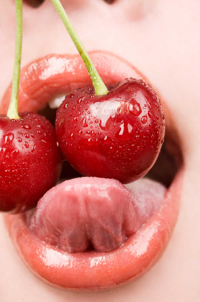 年轻的女人在性的方式吃红樱桃特写