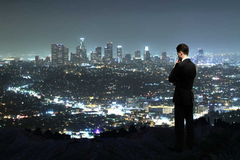 夜晚站在山顶望着城市的男人
