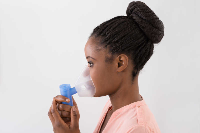 白色背景前使用氧气面罩的非洲女孩
