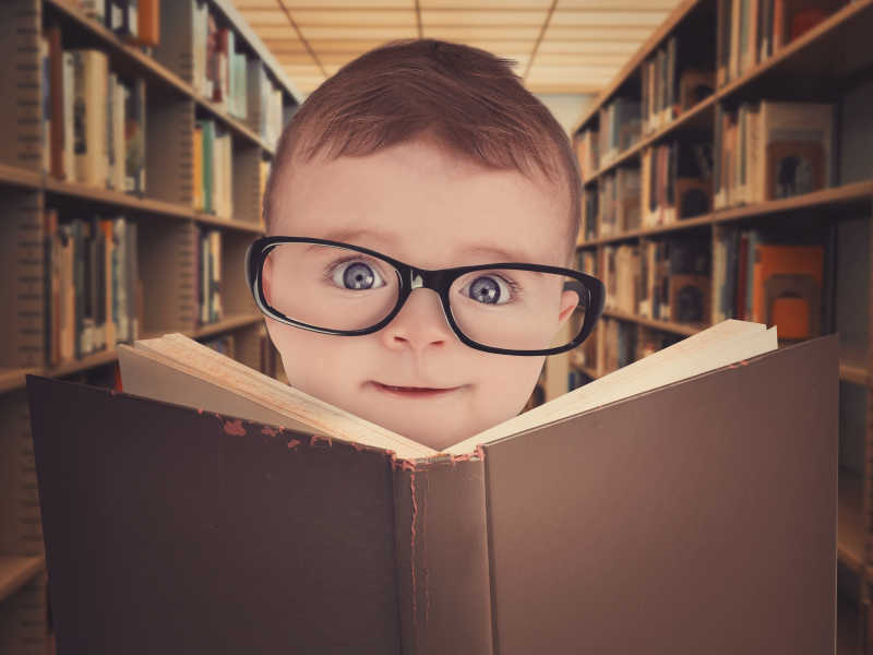 图书馆里拿着书的戴眼镜的婴儿