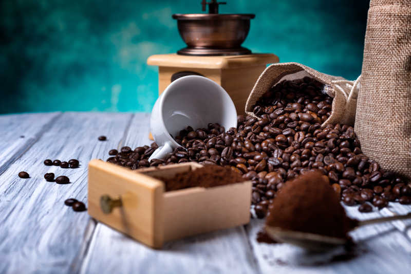 木桌上散落的咖啡豆和咖啡碾磨机
