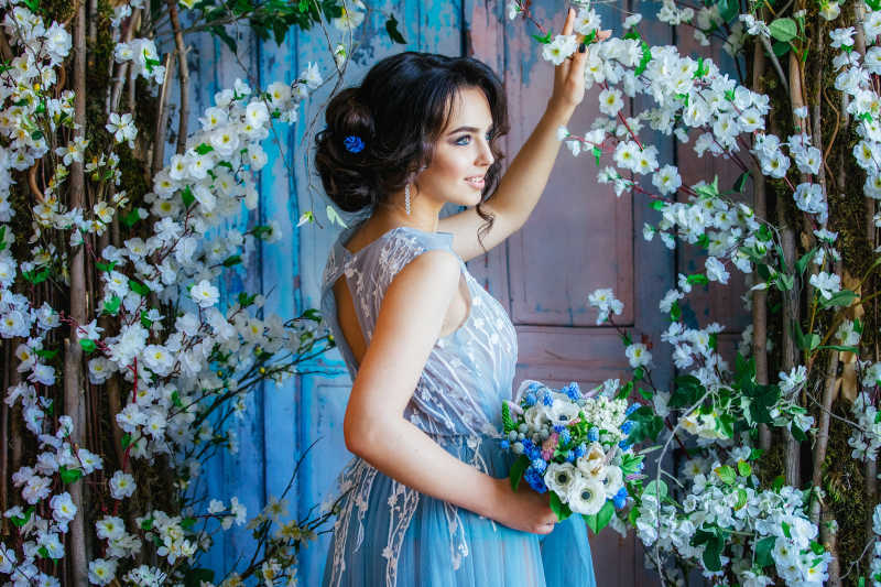新娘穿着华丽的礼服站在花树下面