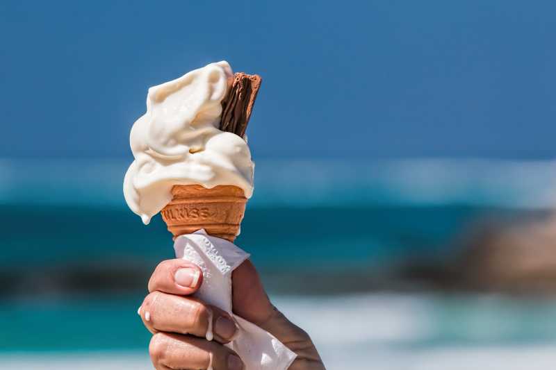 海滩背景手里的香草冰淇淋