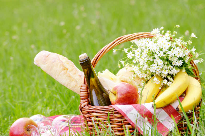 草地上野餐篮中的鲜花和美食