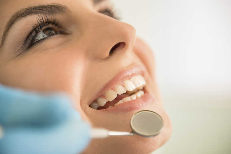 美女患者微笑着让牙医检查牙齿