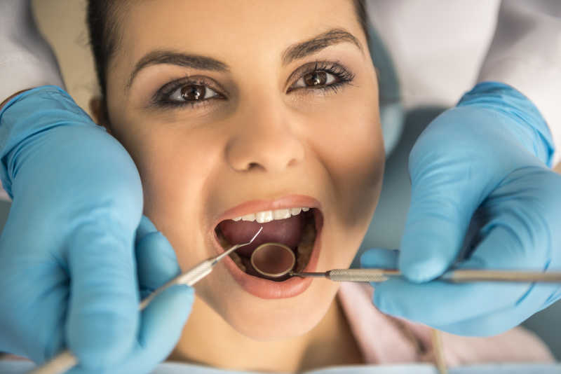 牙医在牙科为美女检查牙齿