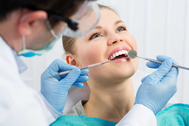 男性牙医在口腔手术前检查病人牙齿