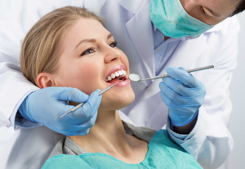 男性牙科医生检查女性牙齿