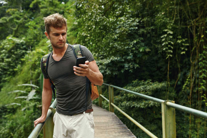 旅游男性在夏季旅游度假时手持智能手机