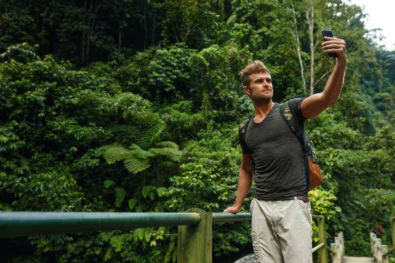 旅游者在热带森林途中用手机自拍照片