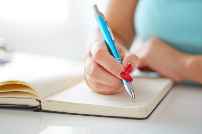 年轻女子在白桌子旁写日记