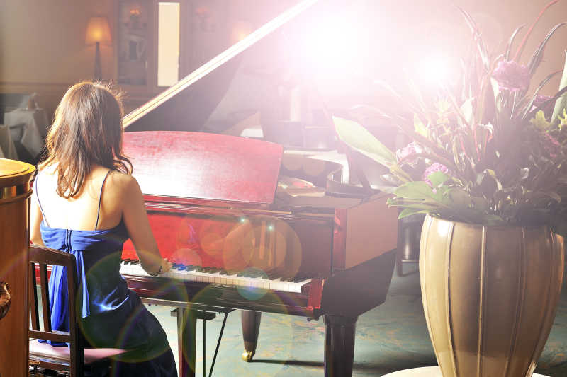 闪光灯下演奏着钢琴的美丽姑娘