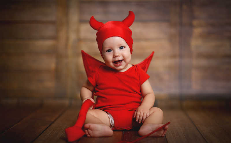 木制背景上恶魔装扮的小婴儿