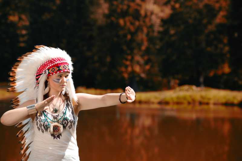 戴印第安头巾在湖边练习的女孩