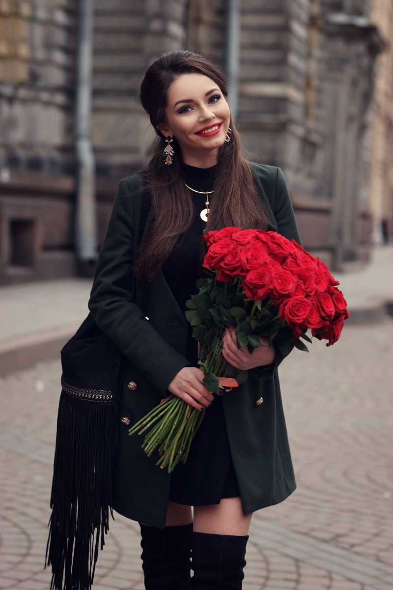 美丽时尚的快乐女孩带着一束红玫瑰