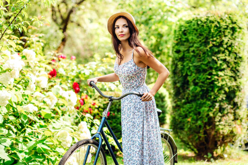 美丽的女子骑自行车在自然花园散步