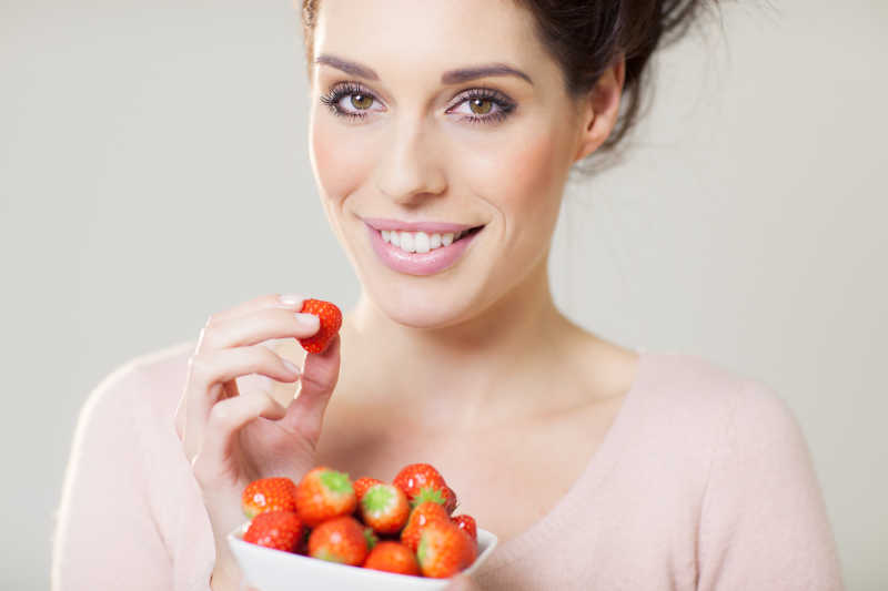 快乐的微笑着吃着草莓的女孩