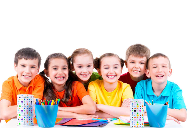 孩子们围坐在摆放着彩笔蜡笔和彩色纸板的桌旁