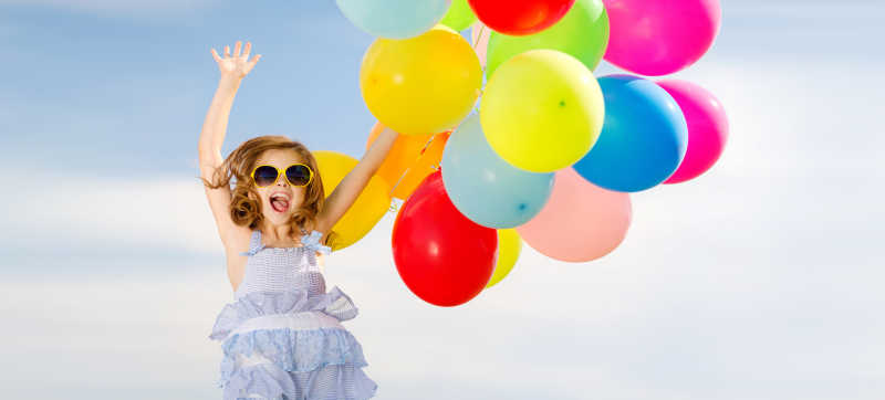 快乐跳跃的女孩带着彩色气球