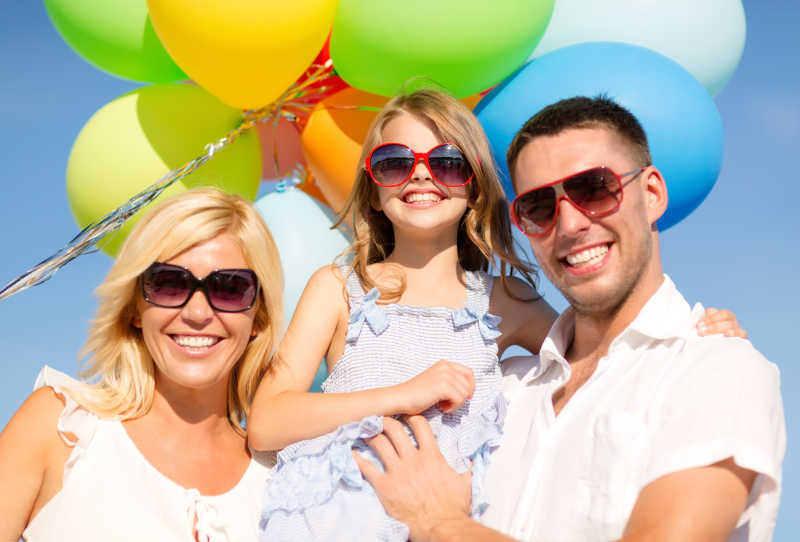 户外彩色气球背景前合影的幸福快乐家庭