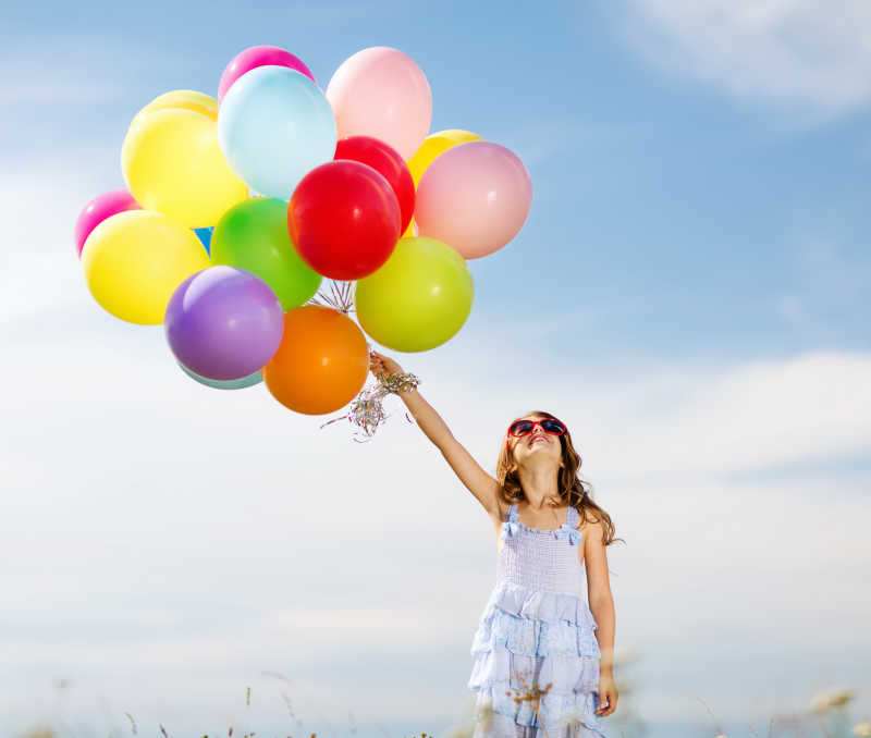 快乐的小女孩手拿彩色的气球
