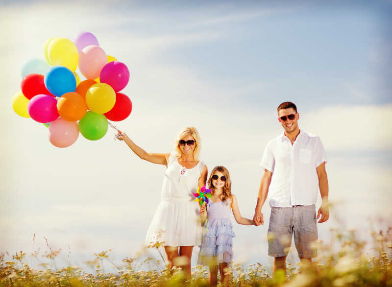 户外快乐的家庭手拿彩色气球