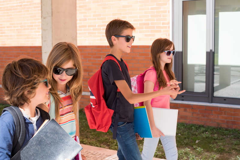 戴着太阳眼镜走在校园里的四个学生