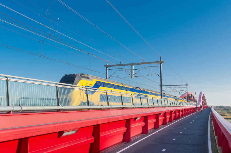 列车驶过荷兰伊斯塞尔河上新建的红铁路大桥