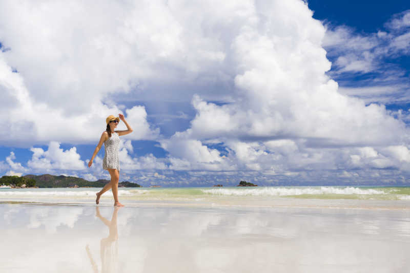 美丽的海边沙滩上在散步的年轻姑娘