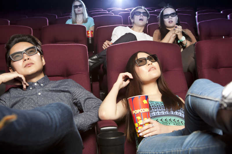 坐在电影院看电影的年轻夫妇