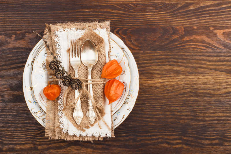 木质背景的橙色干酸浆和银器与装饰餐具