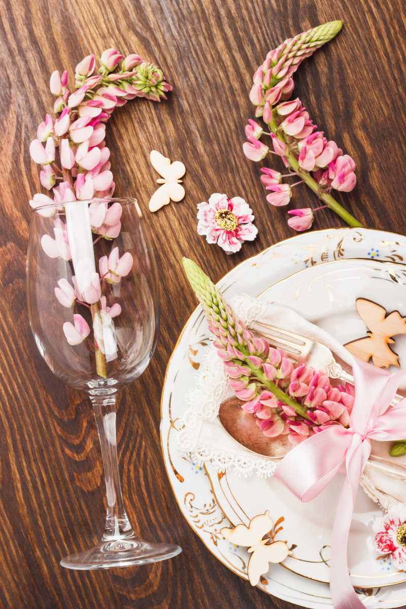 木质背景的粉红色羽扇豆与银器和装饰餐具