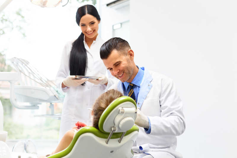 微笑着给小女孩看牙的牙医