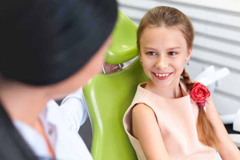 小女孩微笑着看着牙医