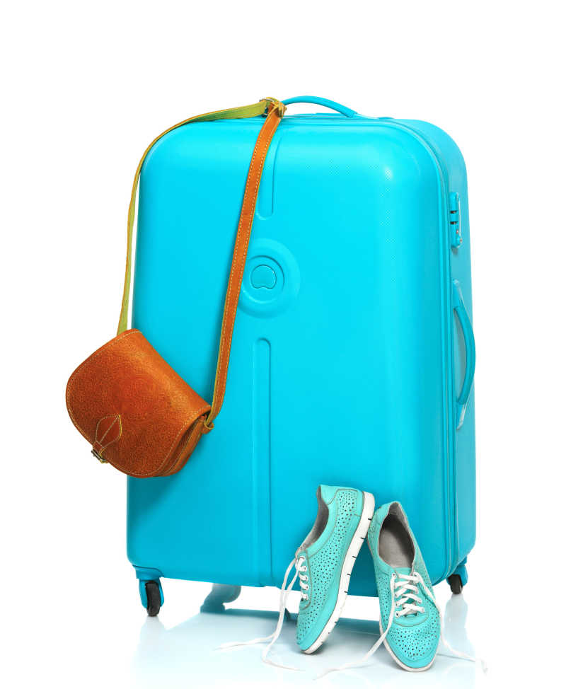 白色背景下运动鞋手提包和蓝色的旅行箱