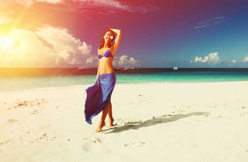 站在海滩上穿蓝裙子的美女