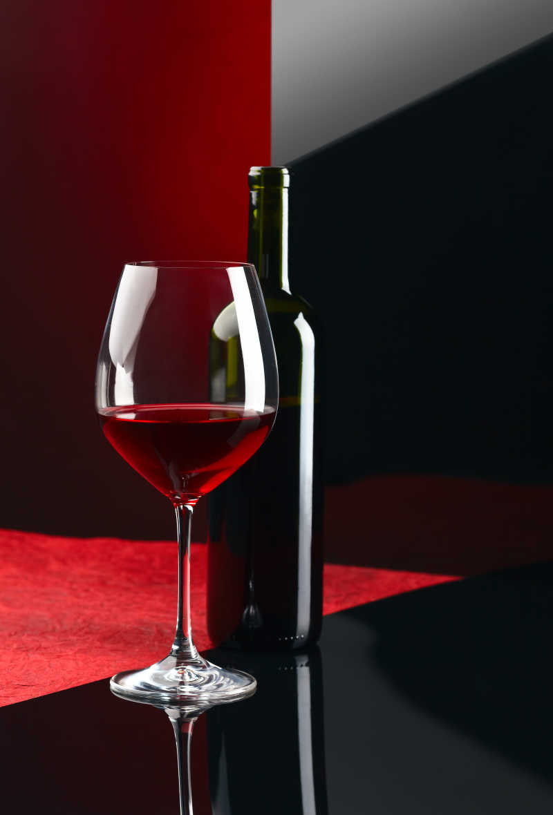 漂亮的放在红黑色背景上的红酒和酒杯