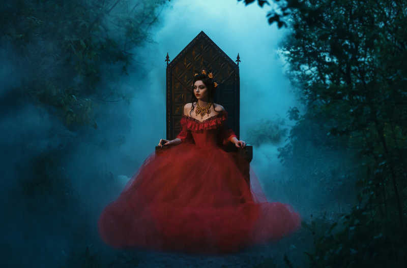 森林里穿红群的邪恶女王风格的女人