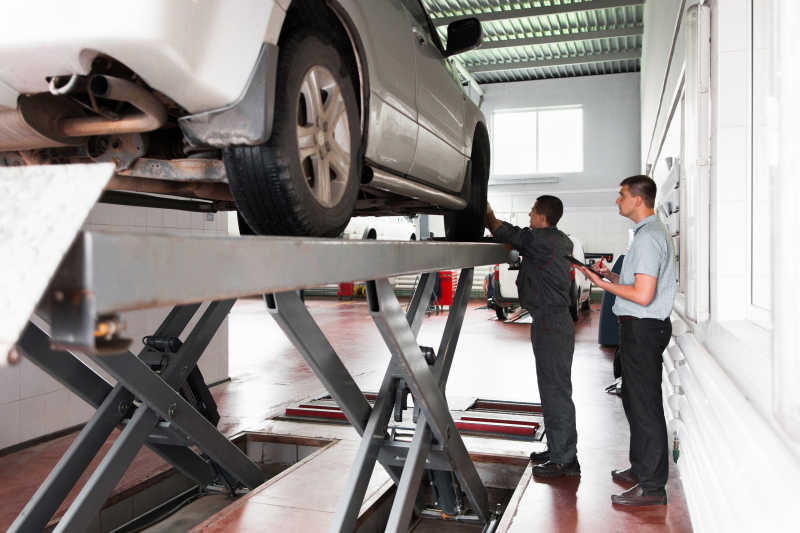 车间里汽车修理工对车辆悬架系统检测
