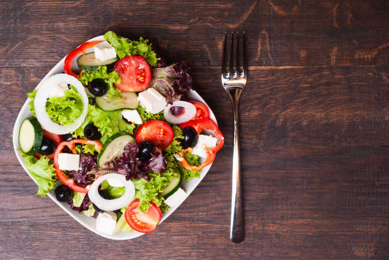 木桌上铁勺旁边的绿色健康沙拉